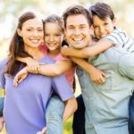 Couple with young kids outside smiling.